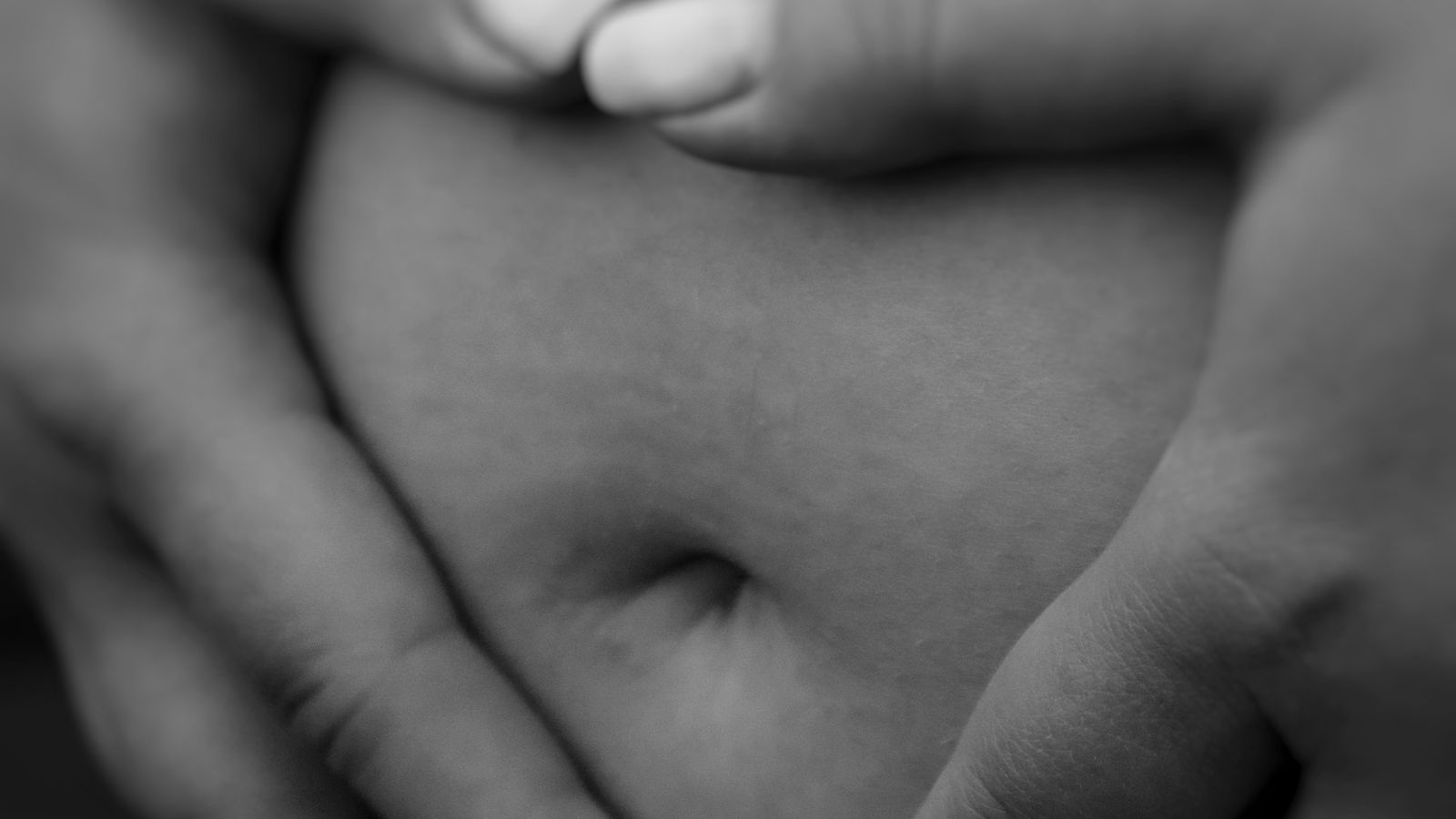 A pregnant person calmly timing contractions on their phone at home in soft evening light